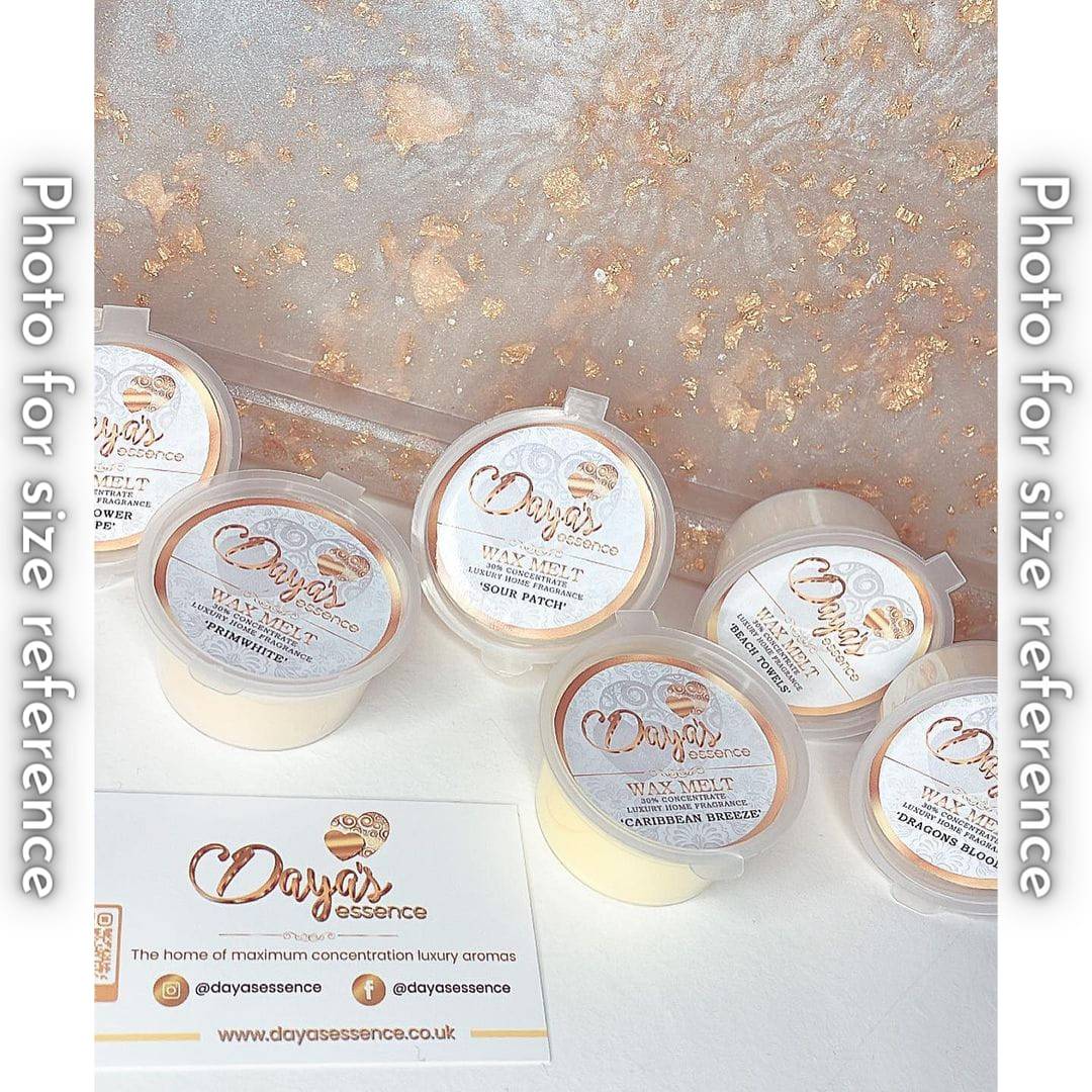 A flat lay of six Daya's Essence wax melts in various scents, including 'Sour Patch,' 'Dragons Blood,' and 'Caribbean Breeze.' A Daya's Essence business card is displayed in the center.