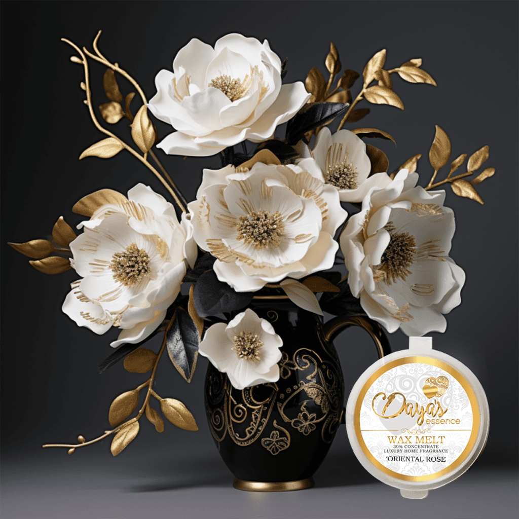 A black and gold vase filled with white roses sits on a surface. In front of the vase is a wax melt labeled "Daya's essence WAX MELT 30% CONCENTRATE LUXURY HOME FRAGRANCE 'ORIENTAL ROSE