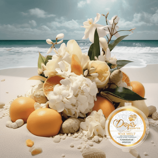 A tropical floral arrangement featuring white flowers, oranges, and seashells is displayed on a sandy beach with the ocean in the background. The arrangement showcases a wax melt product by Daya's Essence called "Caribbean Breeze."