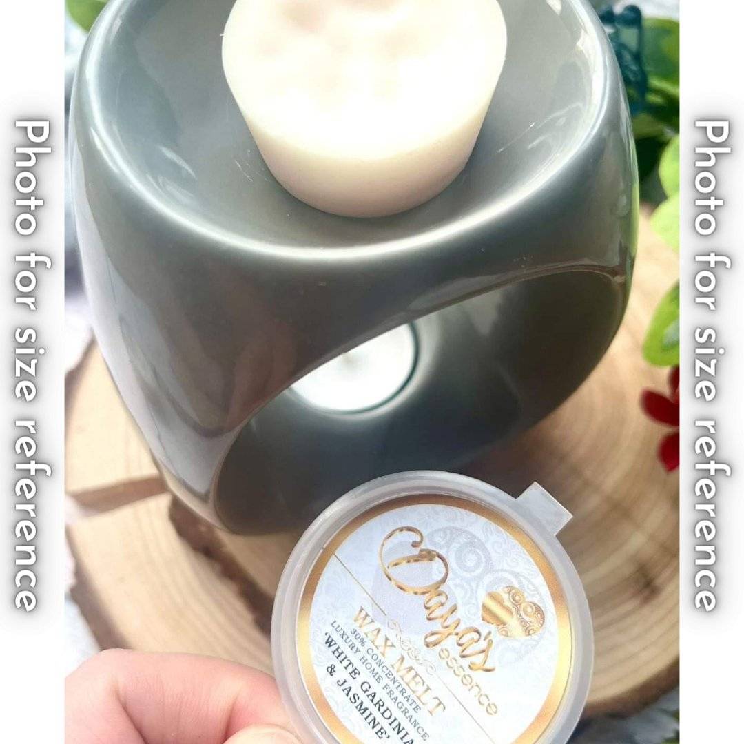 A light grey ceramic wax melt warmer with a white wax melt on top. The wax melt is in a small round plastic container with a label that says "Daya's Essence Wax Melt 30% Concentrate Luxury Home Fragrance 'White Gardenia & Jasmine'."